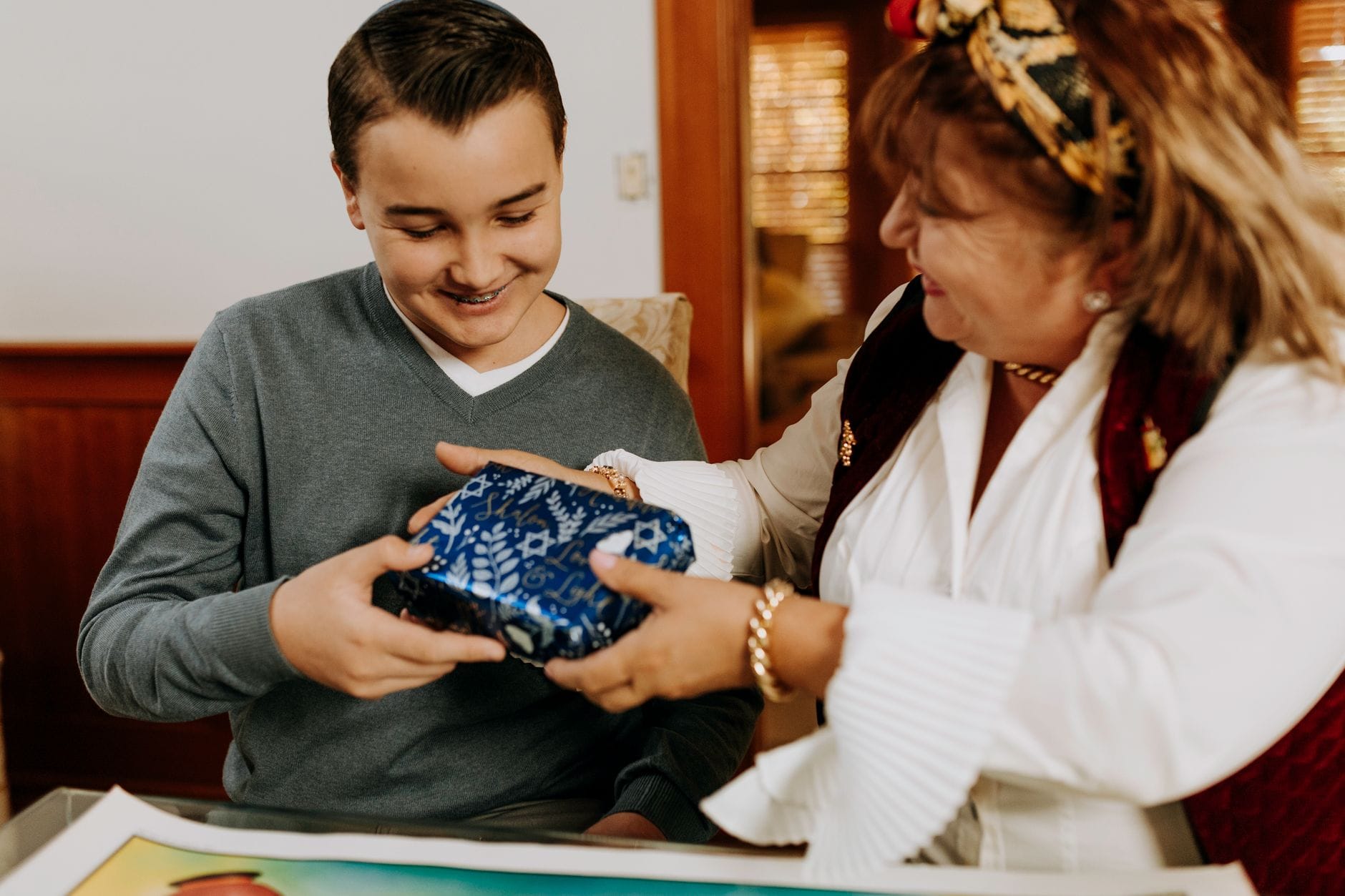 Mama wręcza synowi prezent podczas świątecznego spotkania w domu