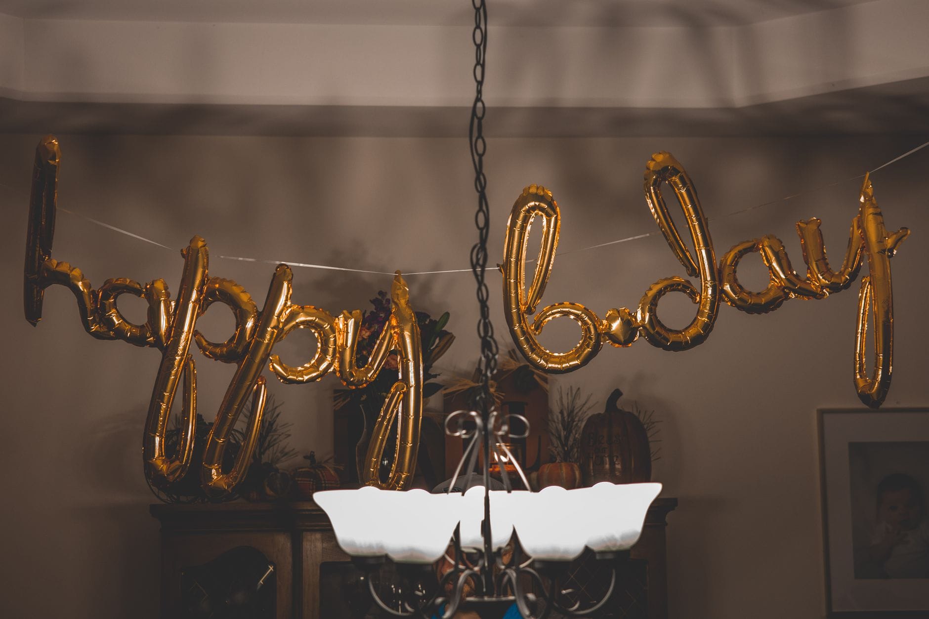 Jak zorganizować imprezę tematyczną w domu: praktyczny poradnik krok po kroku Złote balony happy bday wiszące w pokoju przygotowanym na domówkę